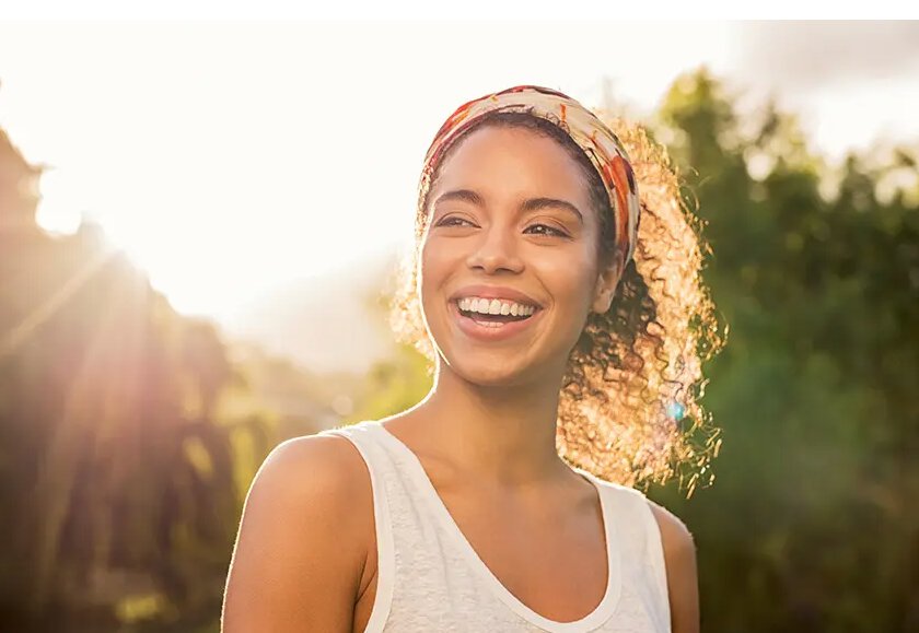 teeth whitening patient model wearing a white tank top, smiling outside
