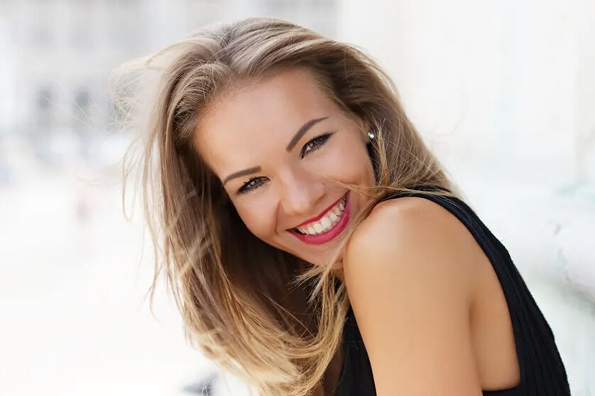 teeth whitening patient model smiling in a black dress and red lipstick