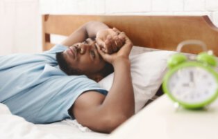 man laying wide awake in bed during the night