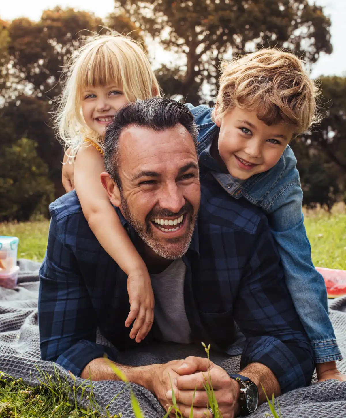 Father smiling with two children on his back outdoors