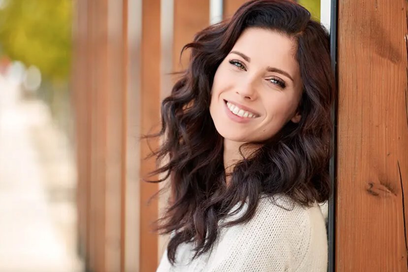 teeth whitening patient model leaning against a wooden post while enjoying the outdoors