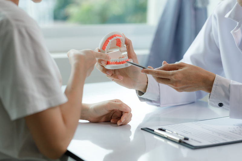 A dentist advises a patient on dental care in a modern clinic, explaining oral hygiene and treatment options with tools or diagrams.