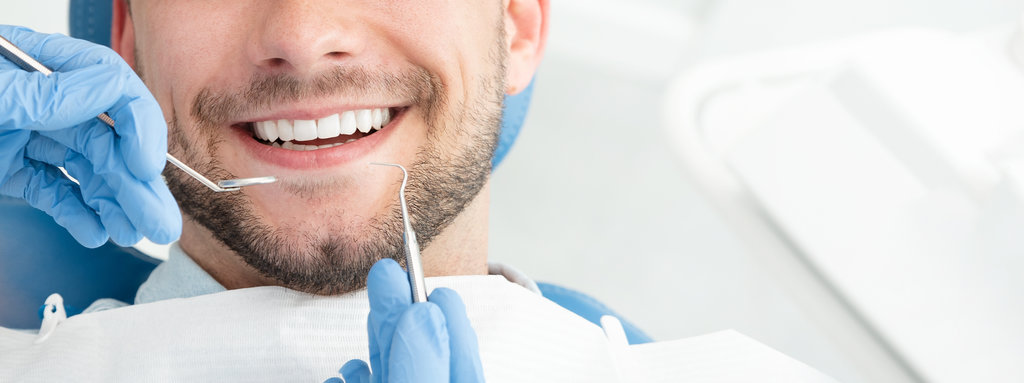 Young man at the dentist. Dental care, taking care of teeth. Picture with copy space for background.