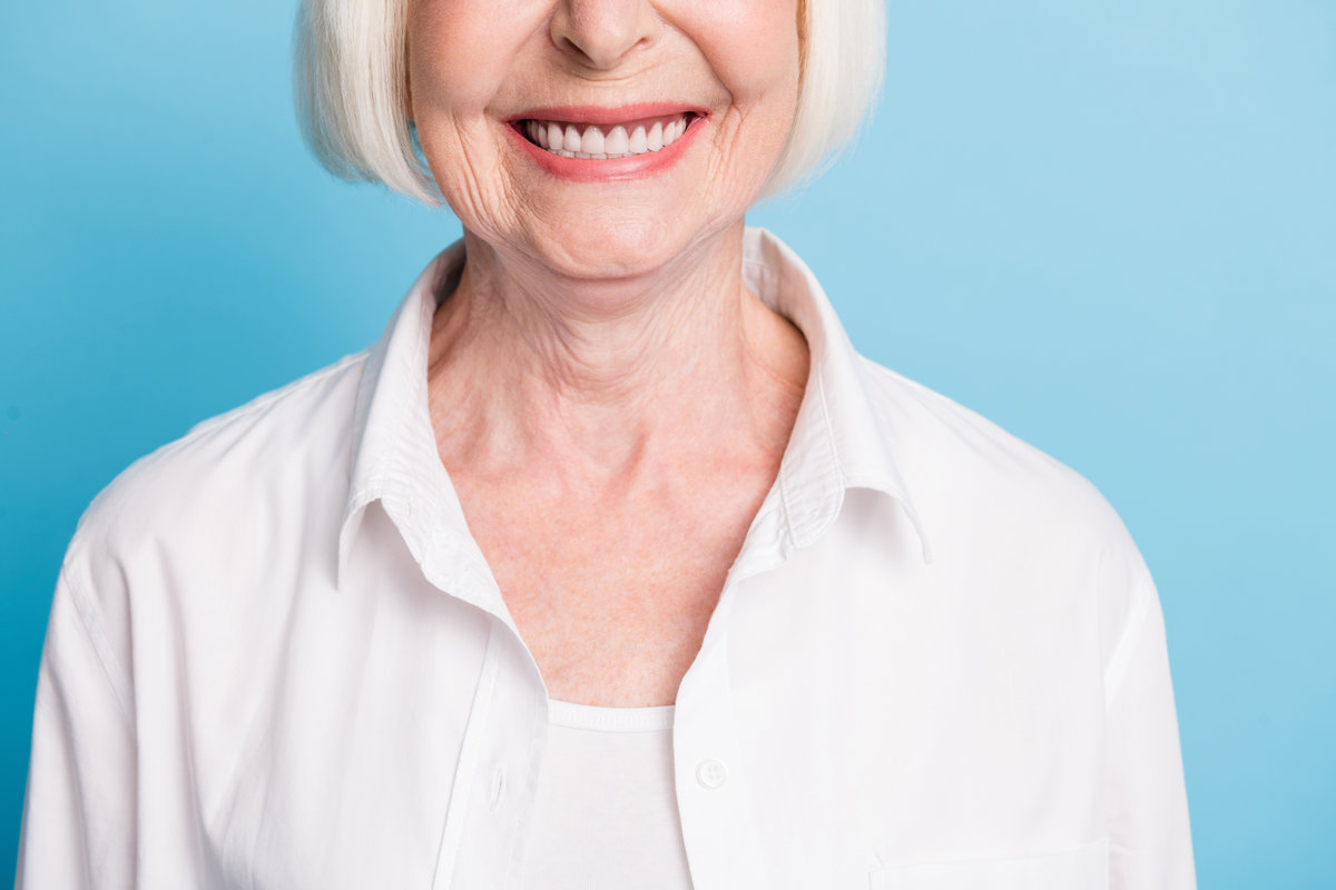 Cropped closeup photo of senior woman smiling with white teeth healthy smile dental veneers isolated on vivid blue color background.