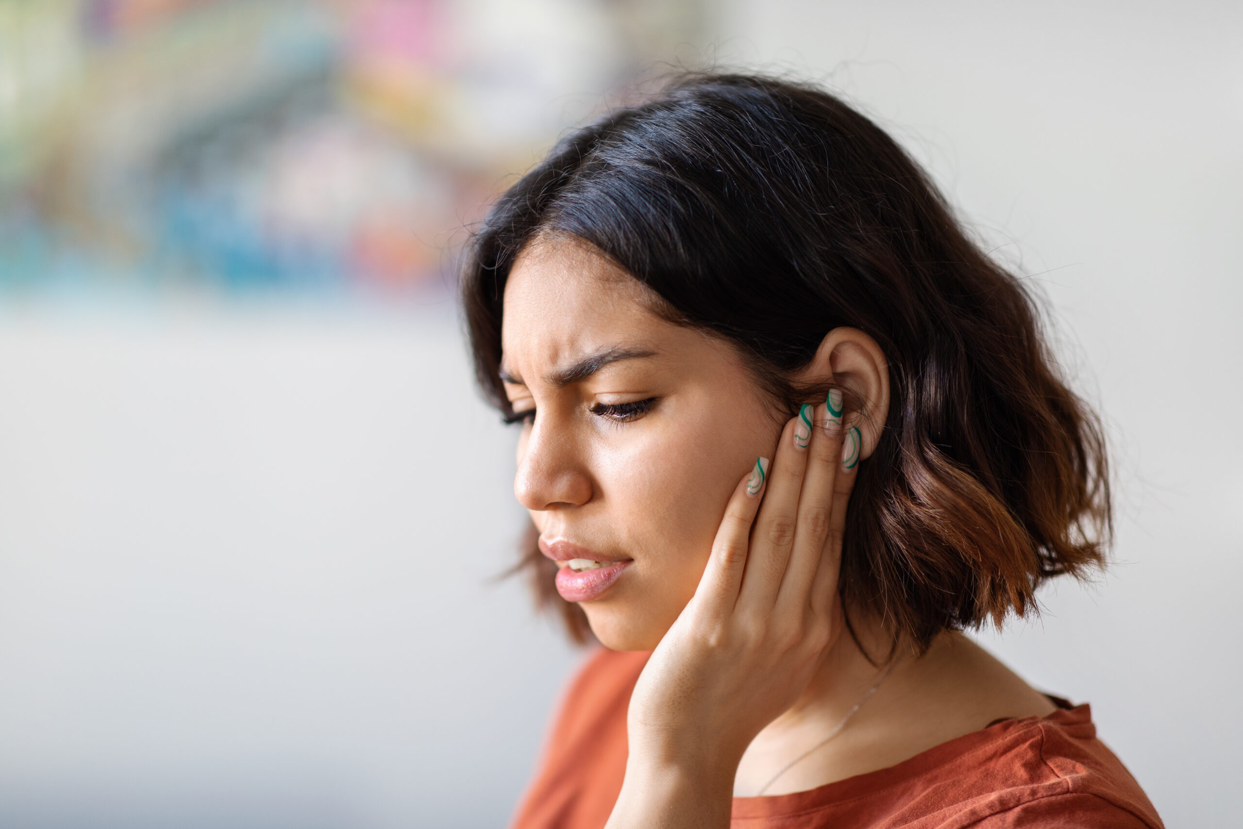 Woman touching ear with a pained expression